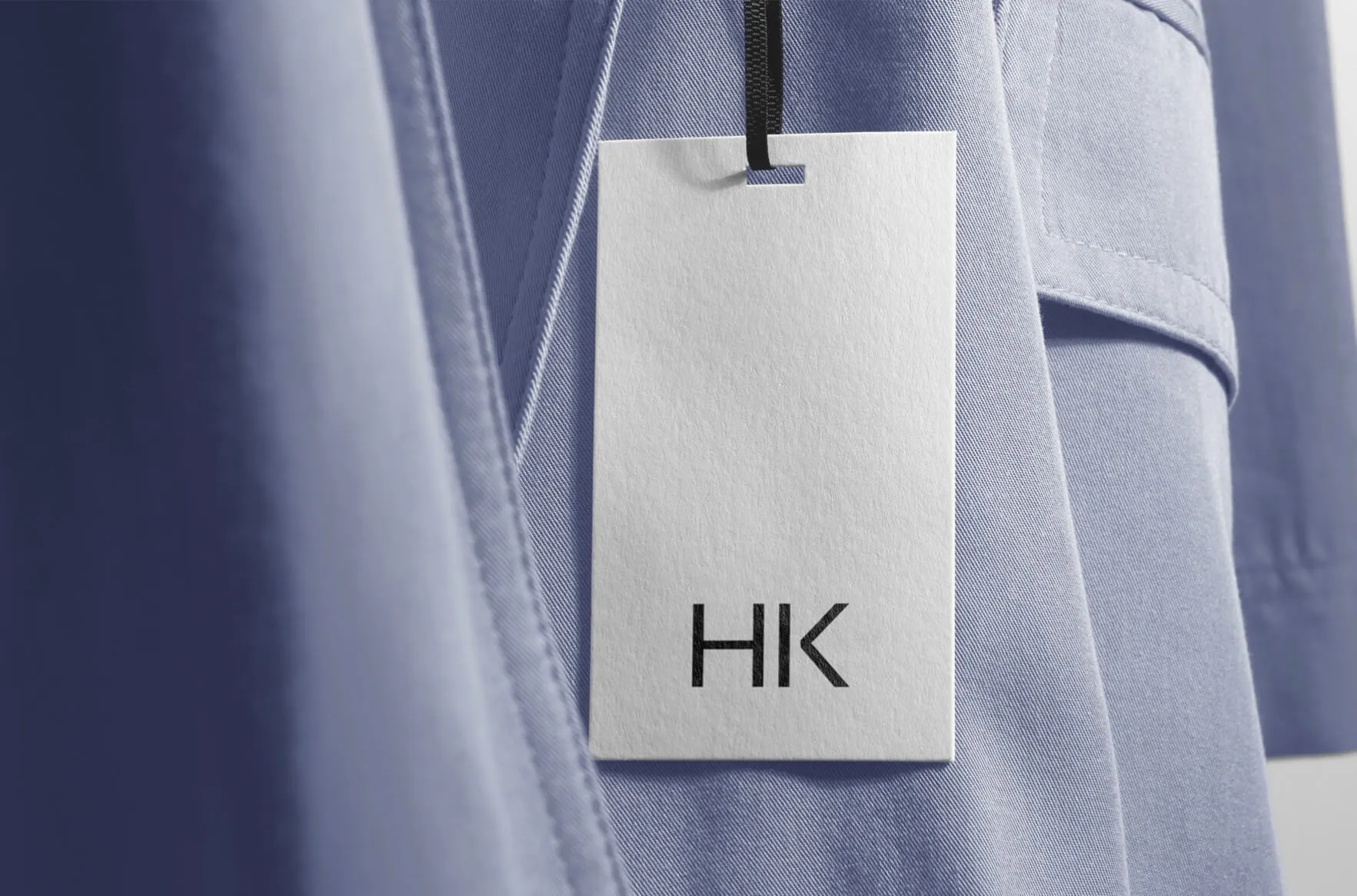 HK Luxe — a white swing tag on a periwinkle wool coat